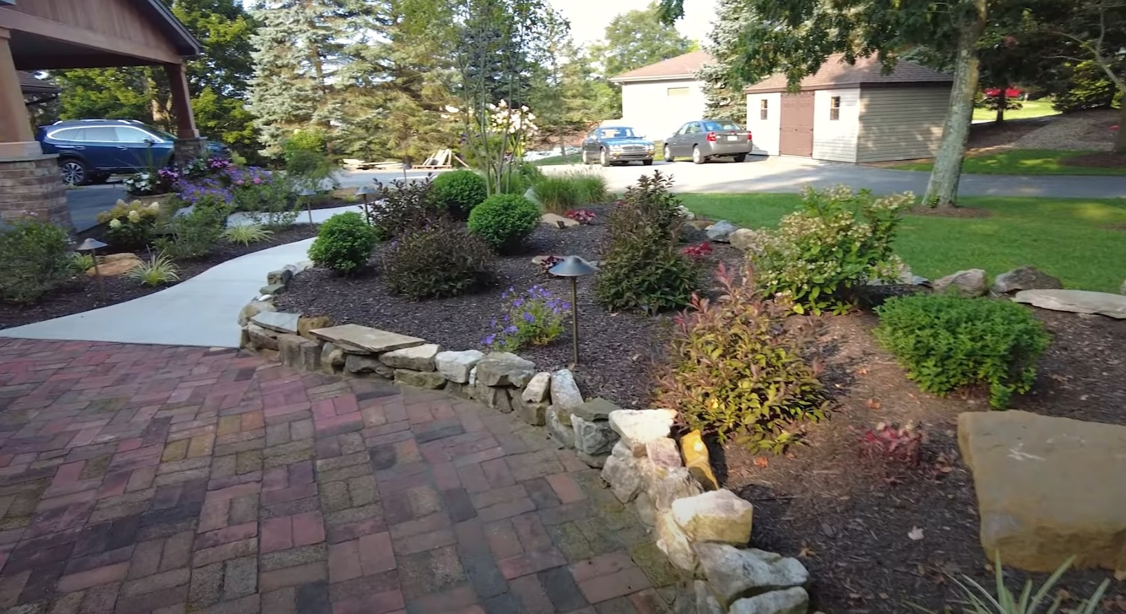 Residential Landscape Renovation - Custom Water Feature and Sustainable Plant Design Front yard landscape transformation featuring natural stone water feature, colorful perennial plantings, and professional hardscaping with decorative boulders