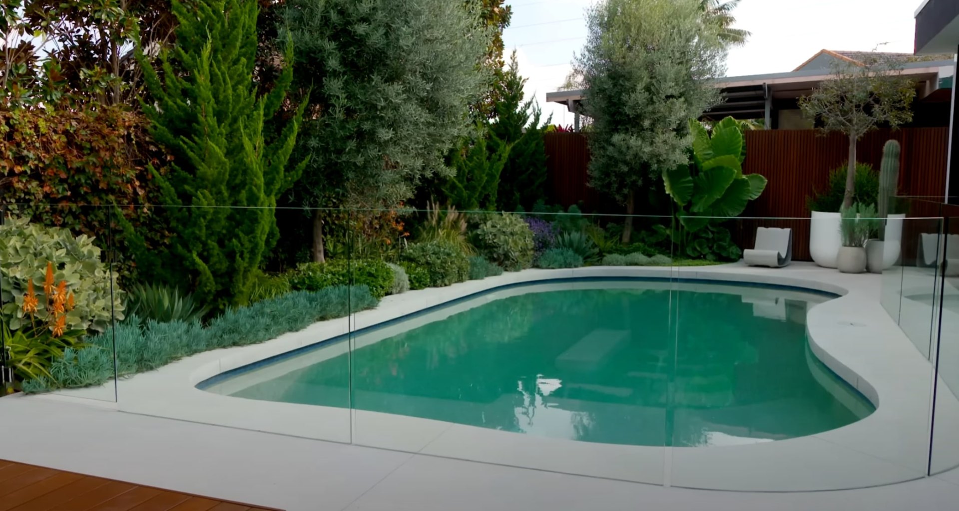 Pool Area Landscaping - Modern Design with Safety Features and Low-Maintenance Plant Selection Luxury pool landscaping with glass safety barriers, drought-tolerant plants, modern outdoor furniture, and professional landscape lighting design