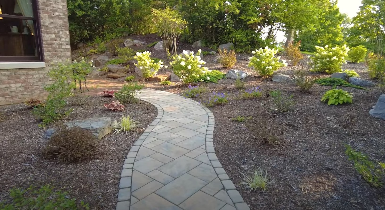 Professional Landscaping with Mulching - Maywood Landscape Design and Maintenance Curved stone pathway through professionally landscaped garden with strategic mulching and plant placement